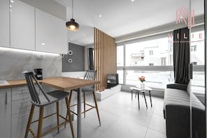 Una cocina moderna con una mesa y sillas de madera, horno empotrado y un ventanal con vistas a la ciudad.