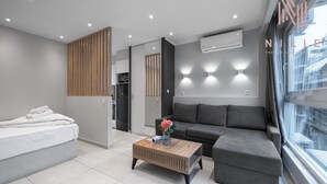 A modern living room with a sofa, a coffee table with a vase, and a bed with rolled towels. - Bonsai Studios & Apartments, Nilie Hospitality MGMT (Thessaloniki)