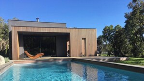 En moderne bygning med pool, hængekøje og en klar blå himmel.