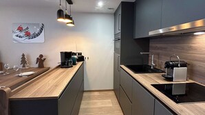 A modern kitchen with dark cabinetry, a wooden countertop, and a built-in stove.