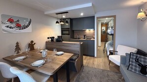 A modern kitchen with dark cabinets, a wooden dining table set with plates and glasses, and pendant lighting.
