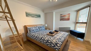 A bedroom with a wooden bed, a bench, a ladder, and artwork on the walls.