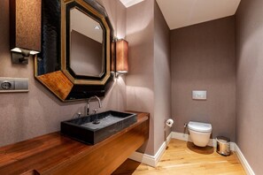 Een moderne badkamer met een houten wastafelmeubel, een grote spiegel en een toilet.