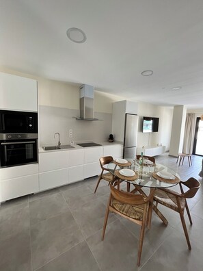 A modern kitchen with white cabinetry, a built-in oven, and a stainless steel range hood. - Arena Coral Luxury Apartment - Main Street - 50 m from the beach (Corralejo)