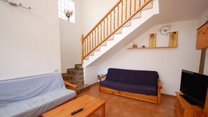 A living room with a staircase, a sofa, a coffee table, and a TV stand. - SAONA VILLAS (VN CEL): villa for 8 people, private pool, air conditioning, wifi (Les Tres Cales)