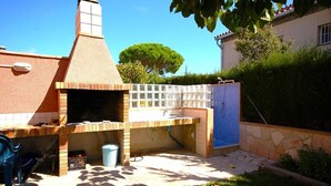 A backyard with a brick barbecue area, a small sink, and a blue plastic chair. - SAONA VILLAS (VN CEL): villa for 8 people, private pool, air conditioning, wifi (Les Tres Cales)