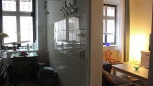 A kitchen with a dining area, a window with curtains, and a radiator. - Quiet & cozy apartment in Südstadt, close to the train station & free parking (Görlitz)