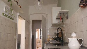 A kitchen with a white kettle, a hanging pot rack, and a clear light fixture. - Quiet & cozy apartment in Südstadt, close to the train station & free parking (Görlitz)