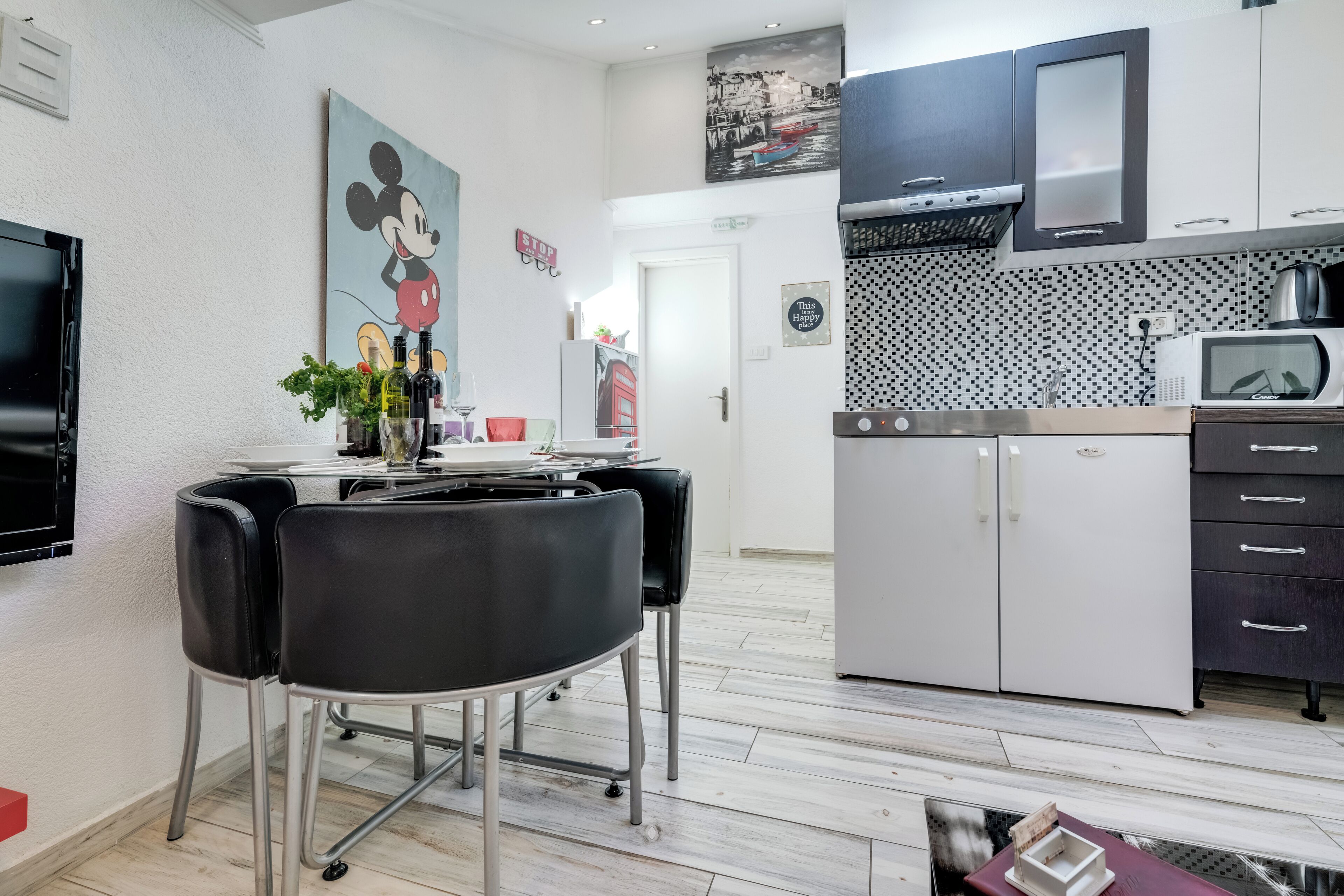 Una cocina moderna con microondas, estufa y armarios. Hay un comedor con mesa y sillas.