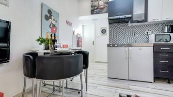 Una cocina moderna con microondas, estufa y armarios. Hay un comedor con mesa y sillas.