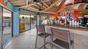 Un espace bar avec un comptoir, des tabourets et un ventilateur de plafond.