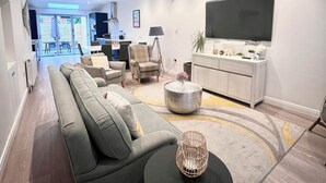 A modern living room with a sectional sofa, a round coffee table, and a flat-screen TV. - Mode Cottage (Lytham St. Anne's)
