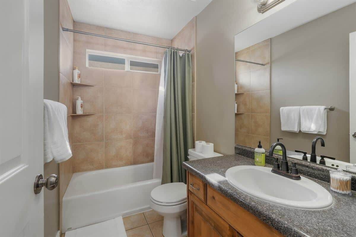 Un baño con bañera, inodoro, lavamanos y espejo.