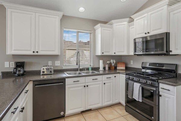 Enjoy cooking in this well-lit kitchen with a gas range, sink, and ample countertop space.