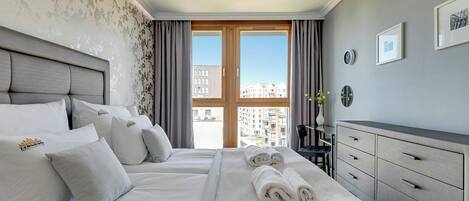 A hotel room with a large bed, a dresser, and a view of buildings through the window.