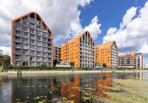 A modern apartment complex with multiple high-rise buildings, a waterfront, and a clear sky. - Aura - Riverside & Parking by Downtown Apartments (Gdansk)