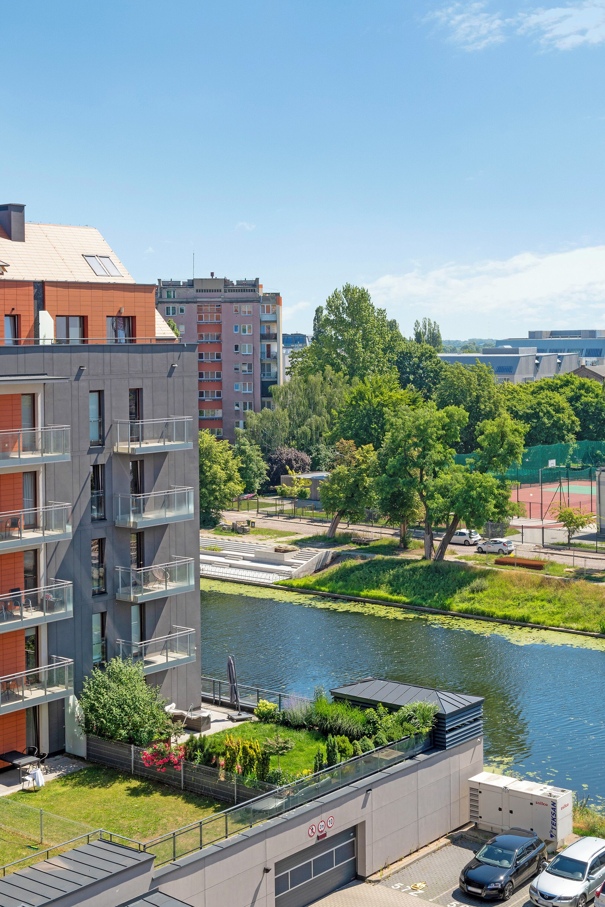 Un moderno condominio con balconi, un cortile interno e vista sul fiume.