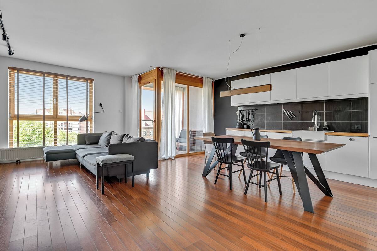 A modern kitchen with white cabinets, a wooden dining table, and a black chair.