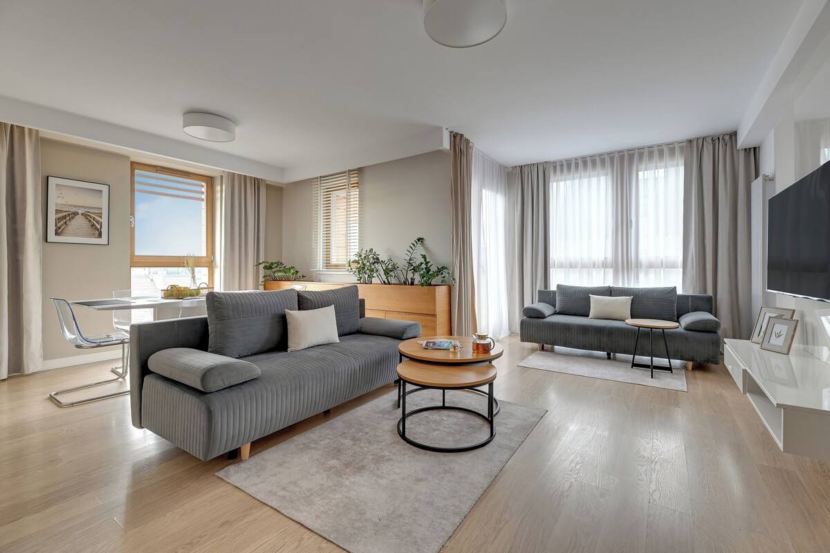A modern living room with a grey sofa, a round coffee table, and a TV.