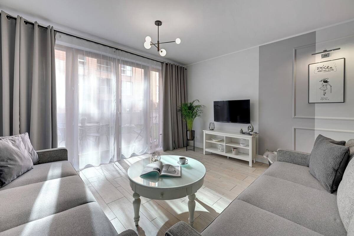 A modern living room with a sofa, a coffee table, a TV, and a bookshelf.