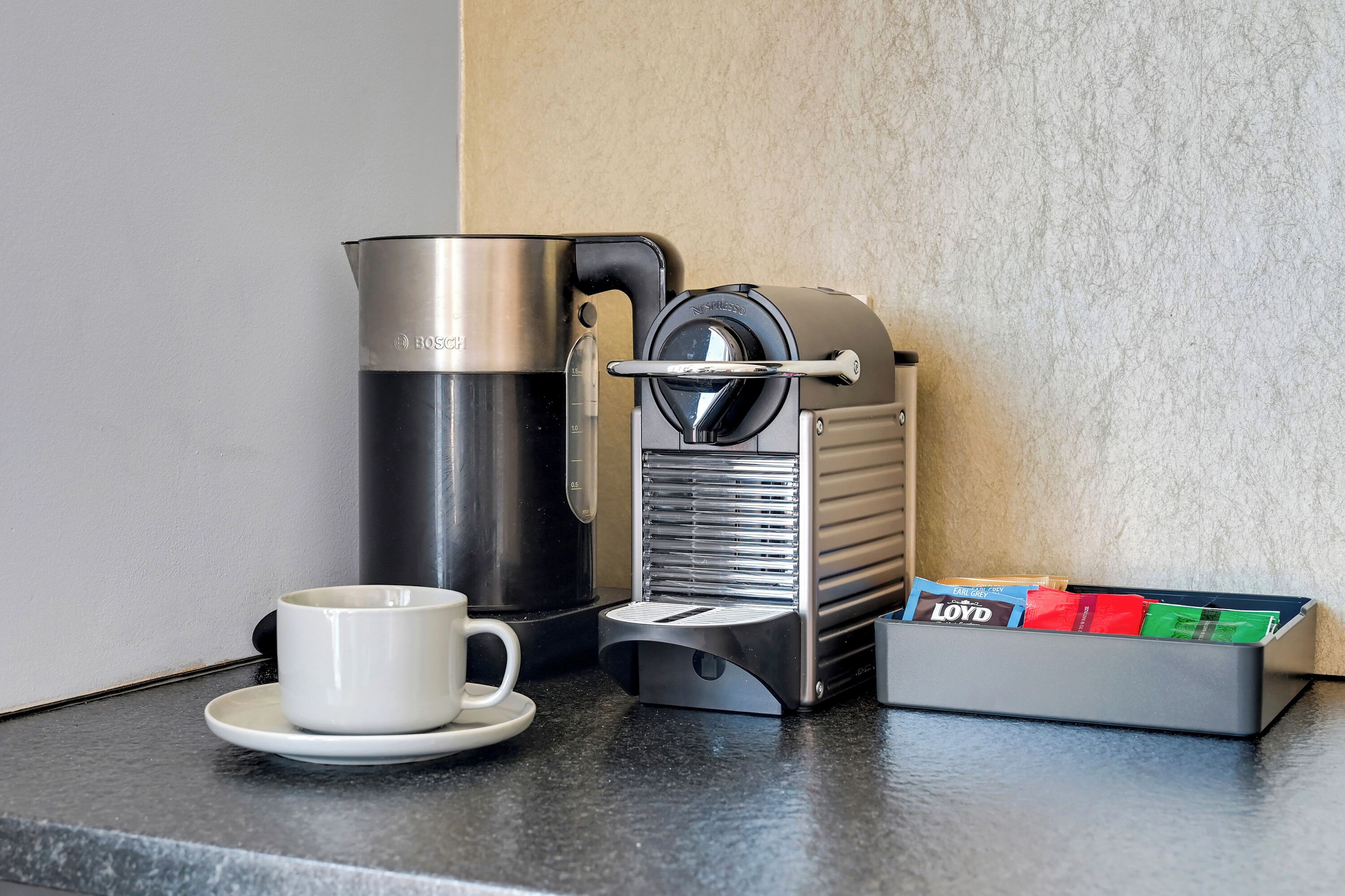 Eine Kaffeemaschine, eine Tasse und ein Kaffee-Pad-Halter auf einer Arbeitsfläche.
