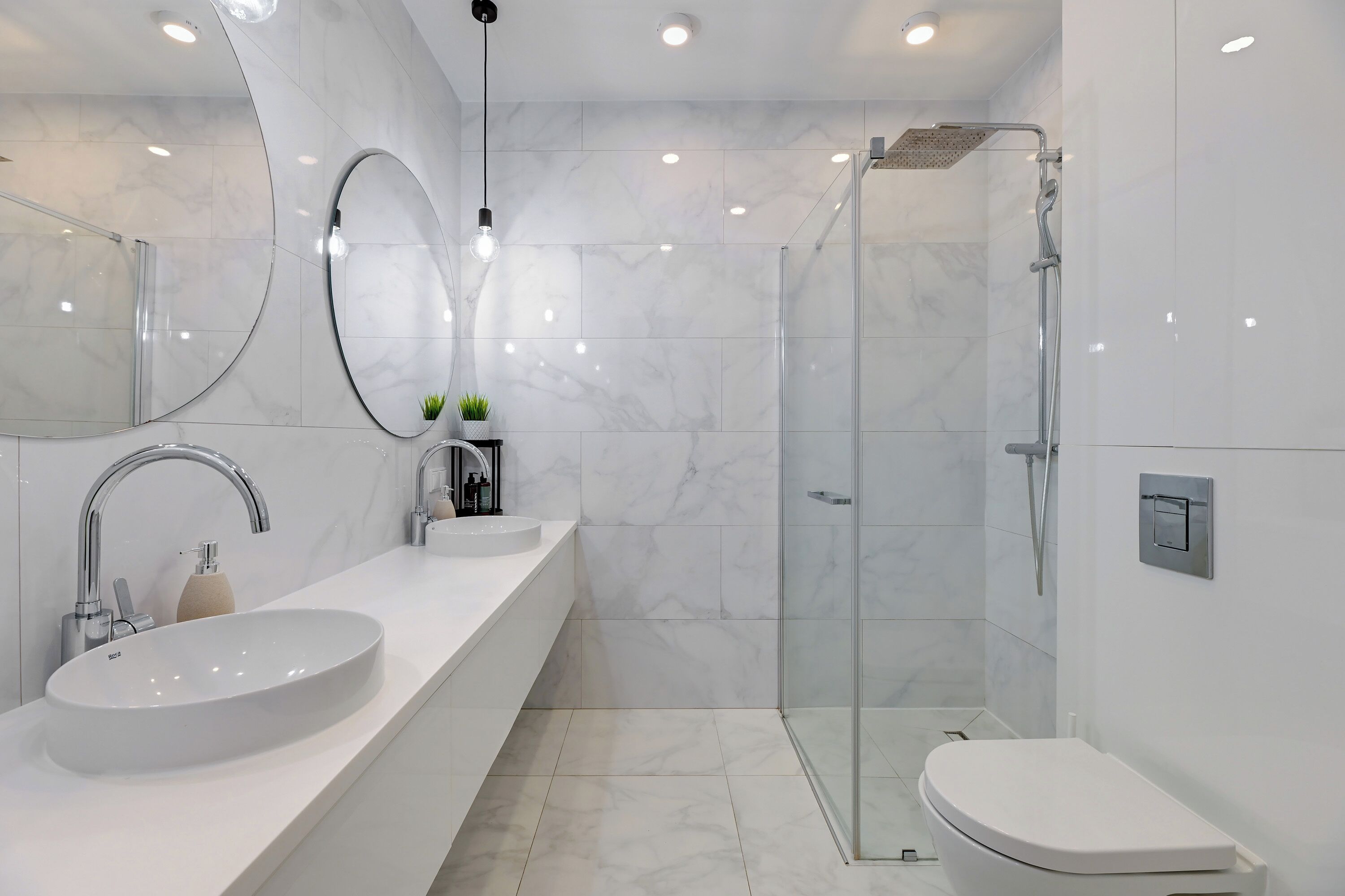 Ein modernes Badezimmer mit einem großen, ovalen Waschbecken, einer Glasdusche und einer Toilette.