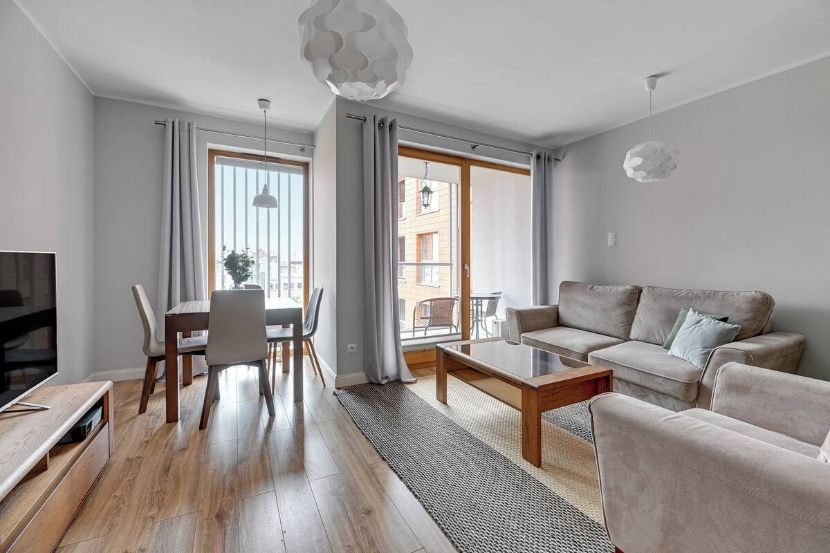 A modern living room with a sofa, coffee table, and dining area.