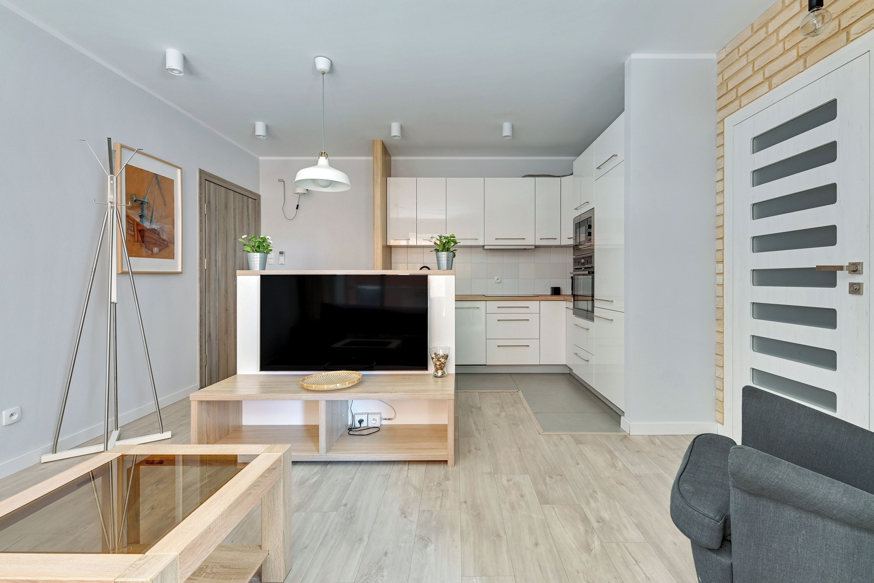 A modern kitchen with white cabinets, a wooden countertop, and a built-in TV.