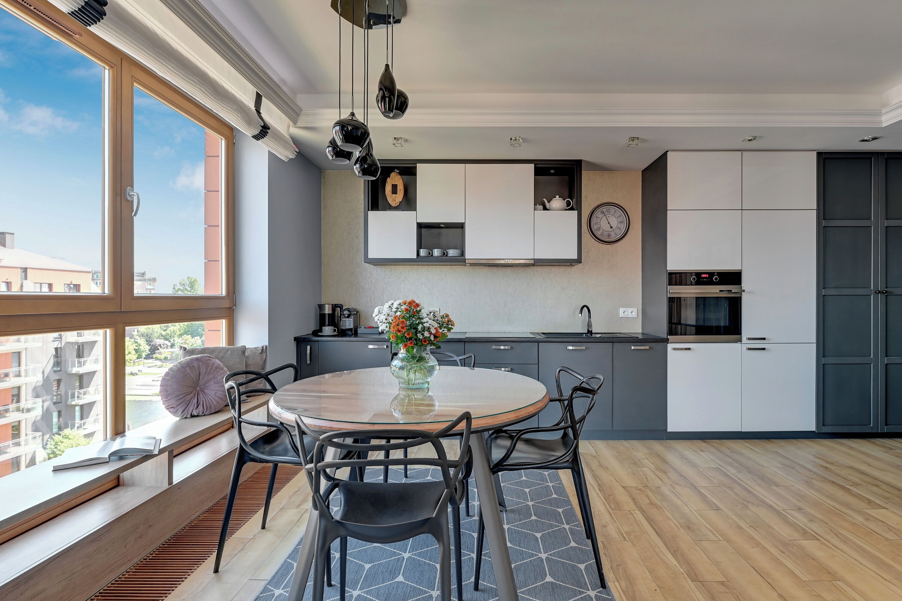 A modern kitchen with a built-in oven, a sink, and a window overlooking a cityscape.