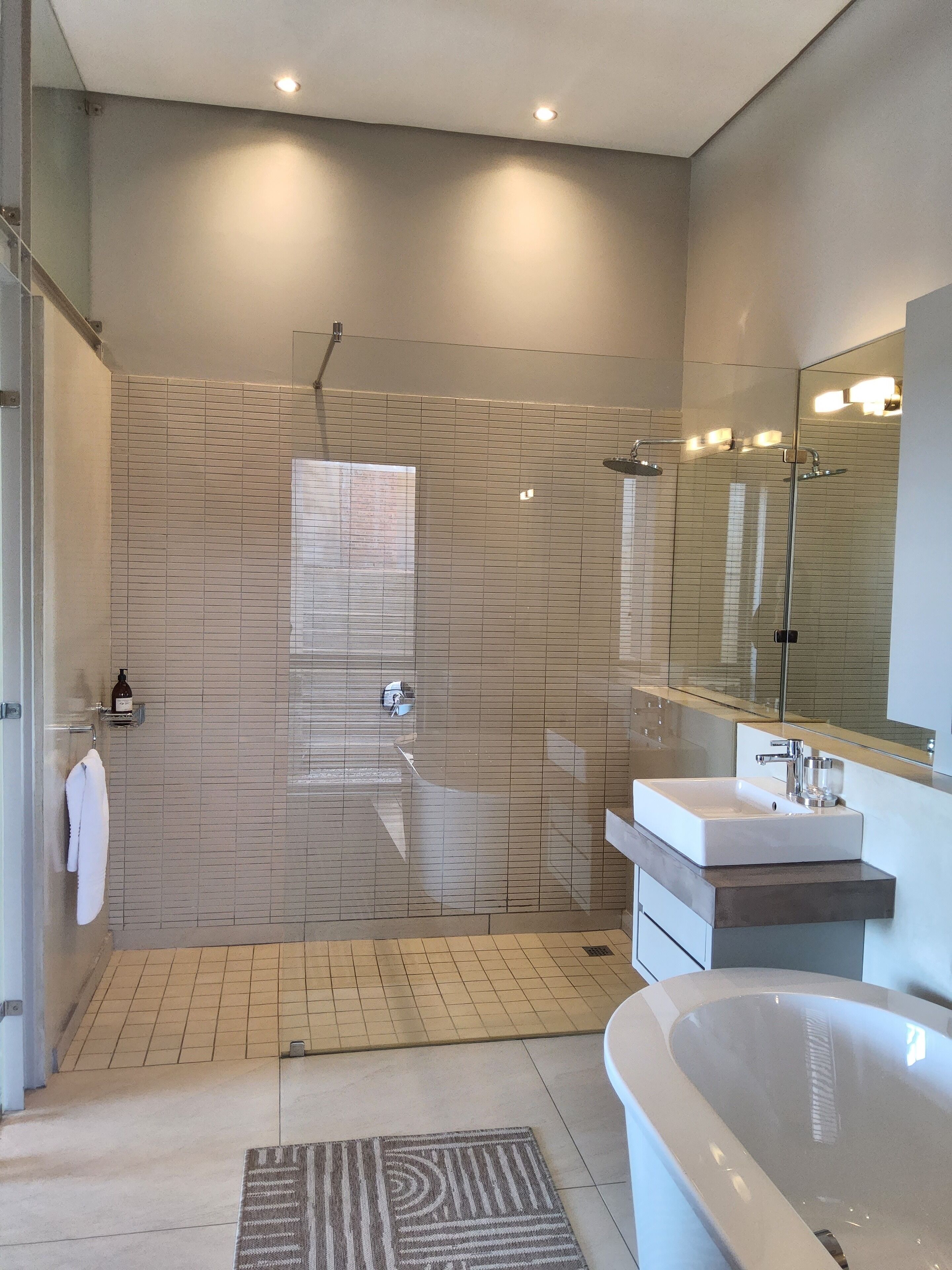 A modern bathroom with a walk-in shower, a freestanding bathtub, and a large mirror.