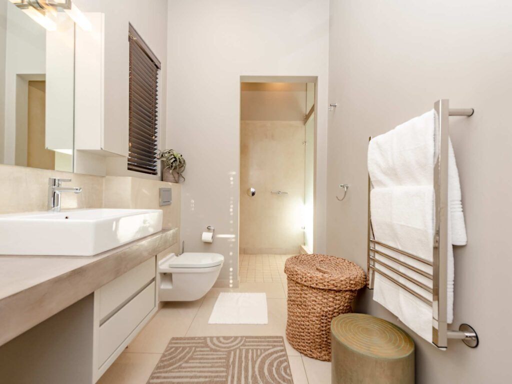 Une salle de bain moderne équipée d’un lavabo, de toilettes et d’un porte-serviettes.