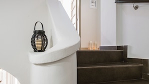 A staircase with a white wall and a black lantern.