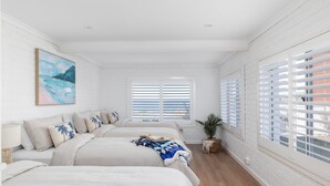 Um quarto com uma janela grande, paredes de tijolos brancos e um quadro na parede.