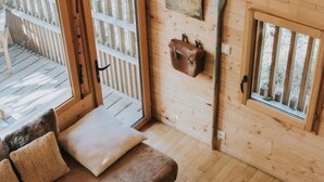 A cozy cabin interior with a wooden floor, a sofa with cushions, a hanging sailboat decoration, and large windows offering a view of the deck. - La Cabane De La Saône, Lyon Country House (Caluire et Cuire)