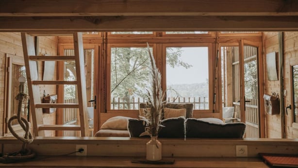 A cozy cabin interior with a wooden bench, a ladder, and a window with a view of trees. - La Cabane De La Saône, Lyon Country House (Caluire et Cuire)