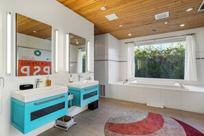 Een moderne badkamer met twee wastafels, een grote spiegel en een bad.