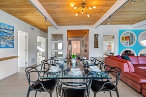 Un coin repas avec une table en verre, des chaises noires et un canapé en cuir rouge.