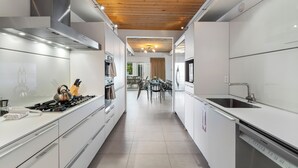 Een moderne keuken met witte kasten, roestvrijstalen apparatuur en een houten plafond.