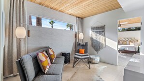 Een moderne woonkamer met een grijze bank, een houten plafond en uitzicht op het omliggende landschap.