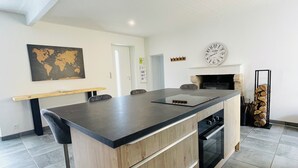 A modern kitchen with a large island, a world map on the wall, and a clock. - House near the sea!  (Grues)