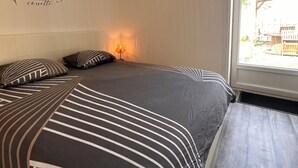 A bedroom with a bed, pillows, a wall decoration, a window, and a lamp. - House near the sea!  (Grues)
