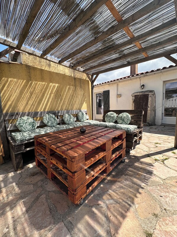 Un espace extérieur aménagé dans un style rustique, avec un banc en bois et une table basse fabriquée à partir de palettes.