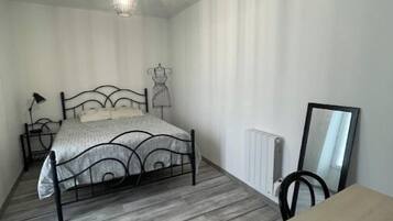 Une chambre à coucher comprenant un lit, une commode, un radiateur, un miroir et un luminaire suspendu.