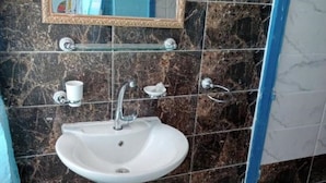 Un baño con un lavabo blanco, un espejo y una pared con azulejos de mármol.