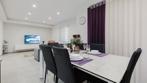 A modern dining area with a white table, black chairs, and purple placemats.
