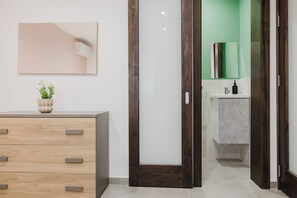 Ein modernes Badezimmer mit grüner Wand, einem weißen Waschbecken und einer Holzkosmetikkommode mit Schubladen.