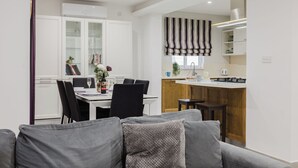 A modern kitchen with a central island, white cabinetry, and a striped valance above the window.