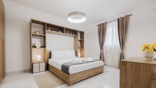 Une chambre à coucher moderne avec un cadre de lit en bois, des tables de chevet, une étagère intégrée et une lampe de chevet.