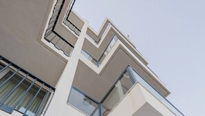 Ein modernes Gebäude mit einem großen Glasbalkon, mehreren Balkonen und freiem Blick auf die Umgebung.