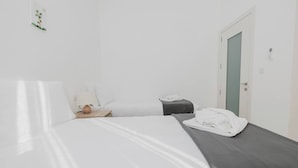Ein Hotelzimmer mit einem Bett, einem Nachttisch mit Lampe, einem kleinen Tisch mit Handtuch und einer Tür.
